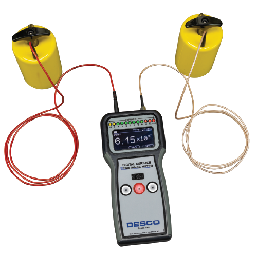 Handheld DESCO digital surface resistance meter connected to two yellow probe units via red and beige test leads.